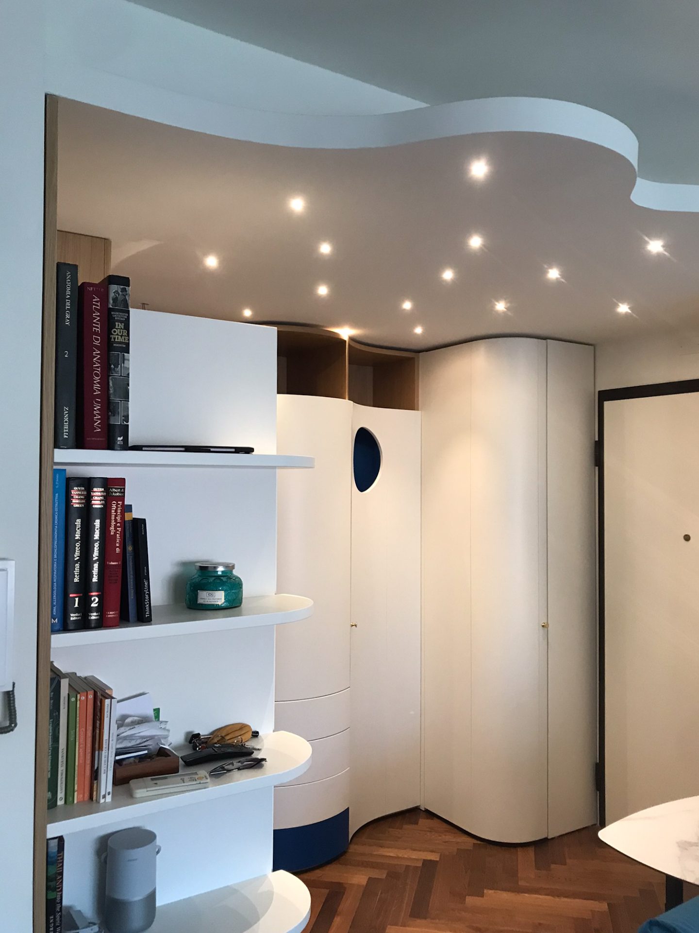 Il mobile su misura dell'ingresso/soggiorno, dalle linee curve, con libreria in cristallo